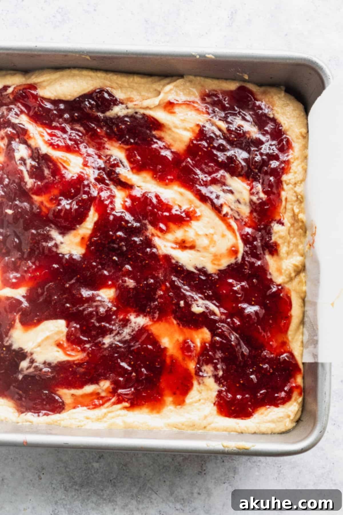 Nostalgic Peanut Butter and Jelly Cheesecake Bars 7 Homemade strawberry jam being spread delicately over the creamy peanut butter cheesecake batter