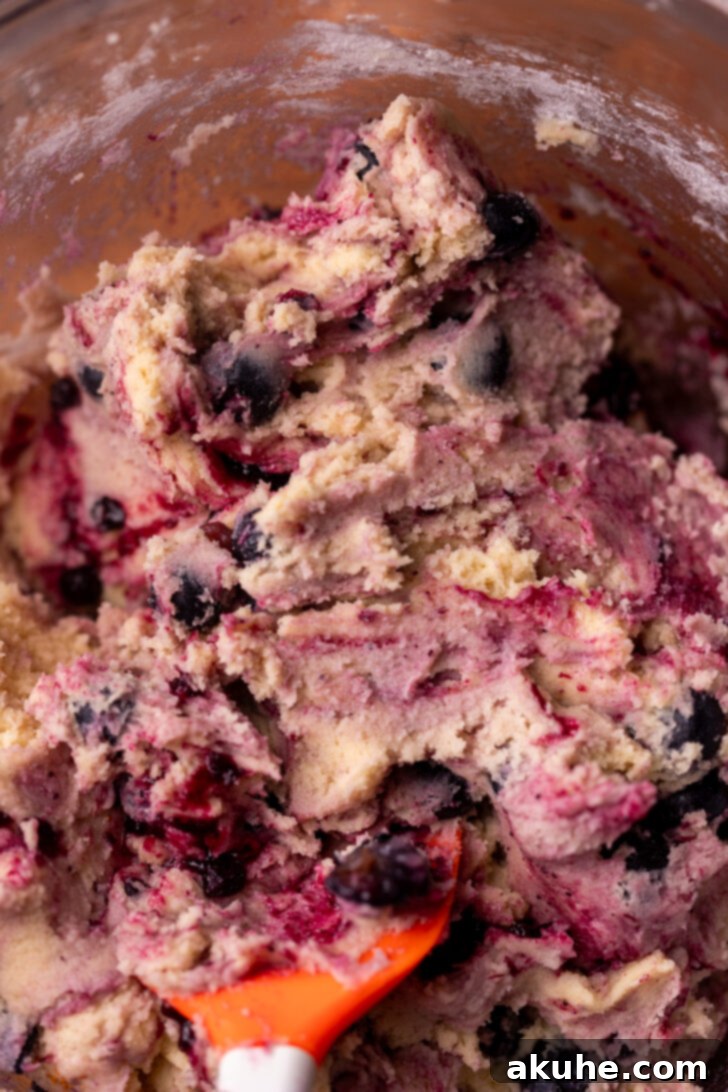 Blueberry Muffin Dream Cookies 5 Close-up of cookie dough in a bowl, showing streaks and ribbons of blueberry jam mixed throughout.