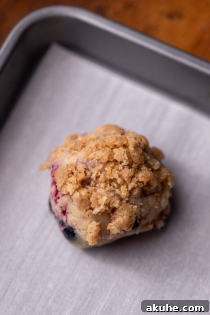 Blueberry Muffin Dream Cookies 6 A scoop of cookie dough with streusel pressed onto the top, placed on a parchment-lined cookie sheet.