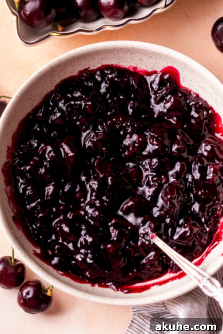 Homemade Cherry Pie Filling 2 Freshly made cherry pie filling in a rustic white bowl, garnished with a few fresh cherries.