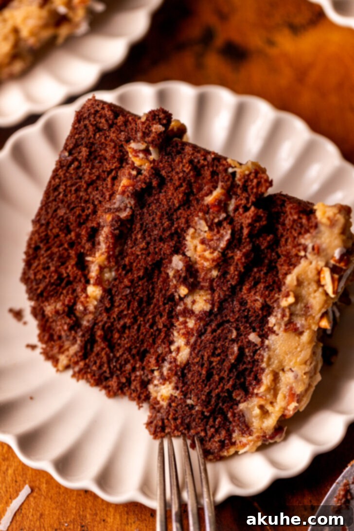 Decadent Chocolate Coconut Pecan Cake 3 A perfectly sliced piece of German chocolate cake resting on a pristine white plate, showcasing the distinct layers and gooey frosting.