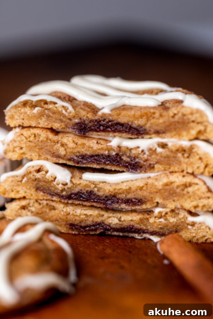 Stack of two cinnamon roll cookies split in half, revealing the cinnamon filling inside.