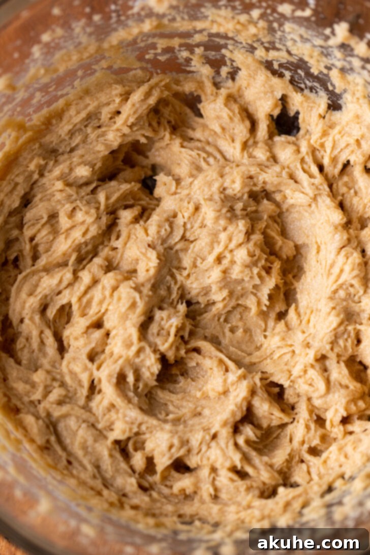 Wet ingredients (butter, sugar, eggs) being mixed in a bowl with an electric mixer.