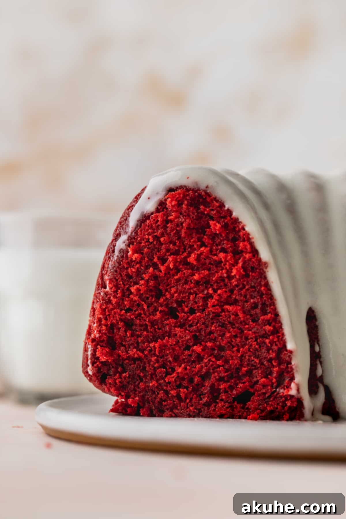 Crimson Crown Bundt Cake 2 A stunning slice of Red Velvet Bundt Cake, revealing its moist, vibrant red interior and a generous swirl of creamy white glaze.