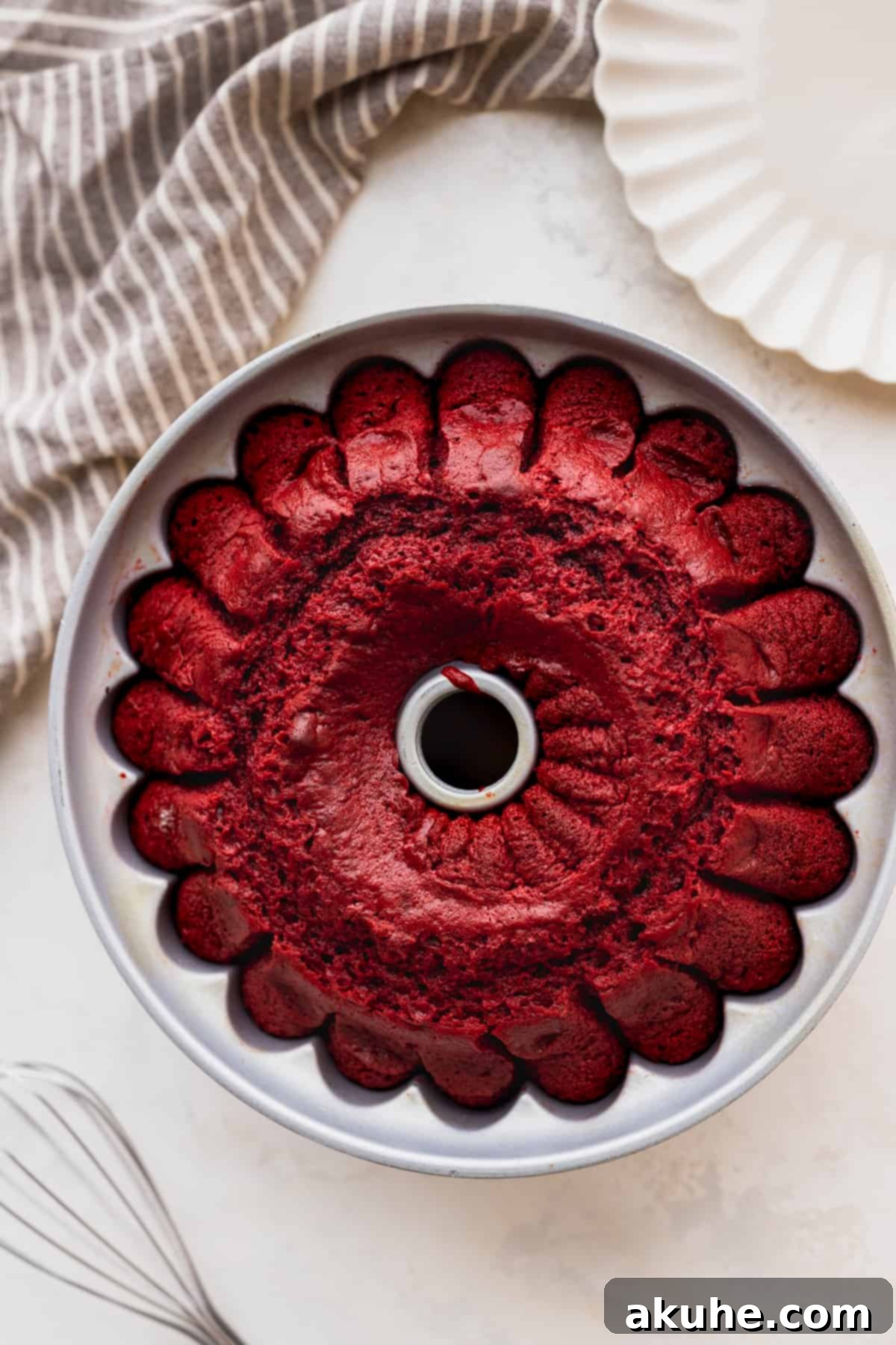 Crimson Crown Bundt Cake 7 A golden-brown baked bundt cake resting in its pan, fresh from the oven, cooling before unmolding.