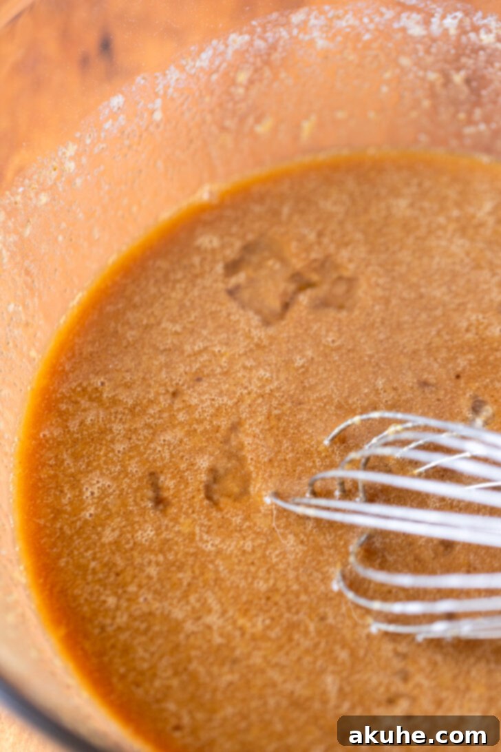 Harvest Apple Cider Donuts 4 Wet ingredients for apple cider donuts, including reduced cider, whisked together in a mixing bowl.