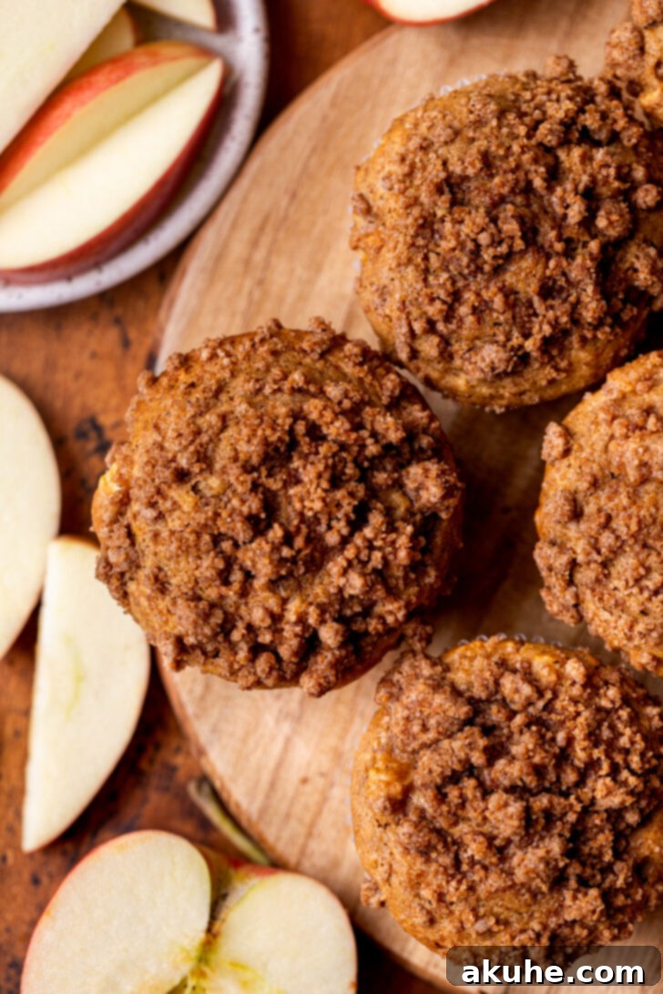 Golden Apple Muffins 3 A top-down view of freshly baked apple muffins, beautifully arranged on a rustic wooden board, showcasing their golden-brown crumb topping.
