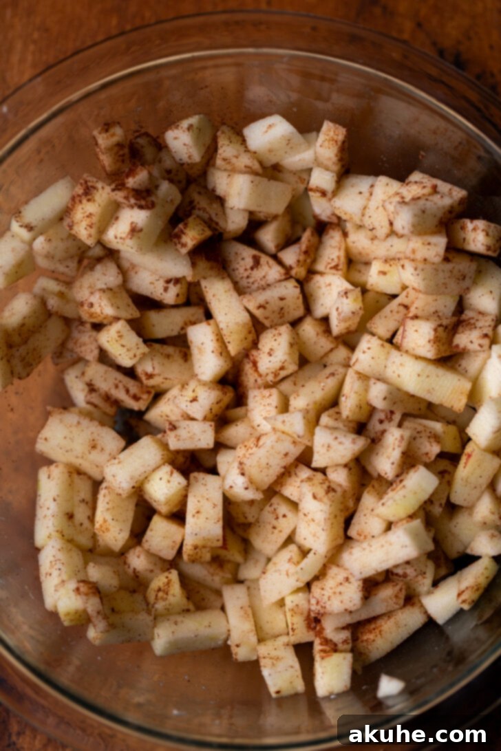 Golden Apple Muffins 4 Freshly diced apples in a bowl, generously coated with flour and cinnamon, ready to be incorporated into the muffin batter.