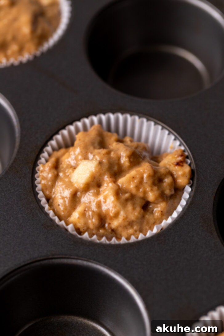 Golden Apple Muffins 7 Muffin batter generously scooped into muffin pan liners, filled almost to the very top, ready for the crumb topping.