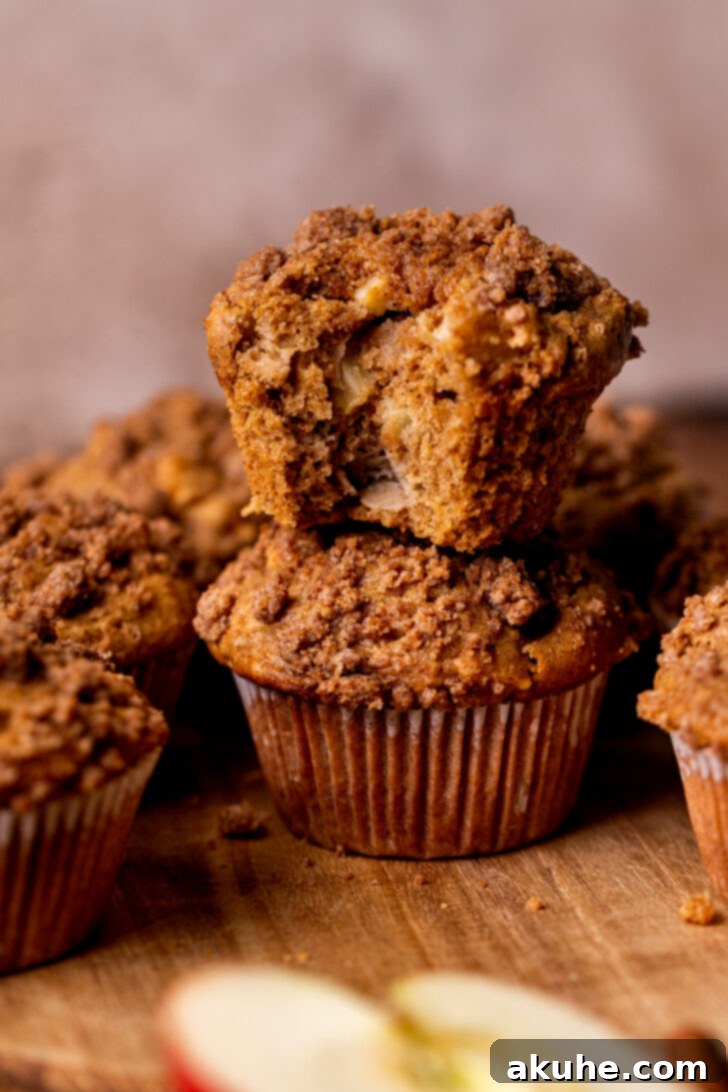 Golden Apple Muffins 10 Two perfectly baked apple muffins with a golden crumb topping, stacked artfully, highlighting their delicious texture.