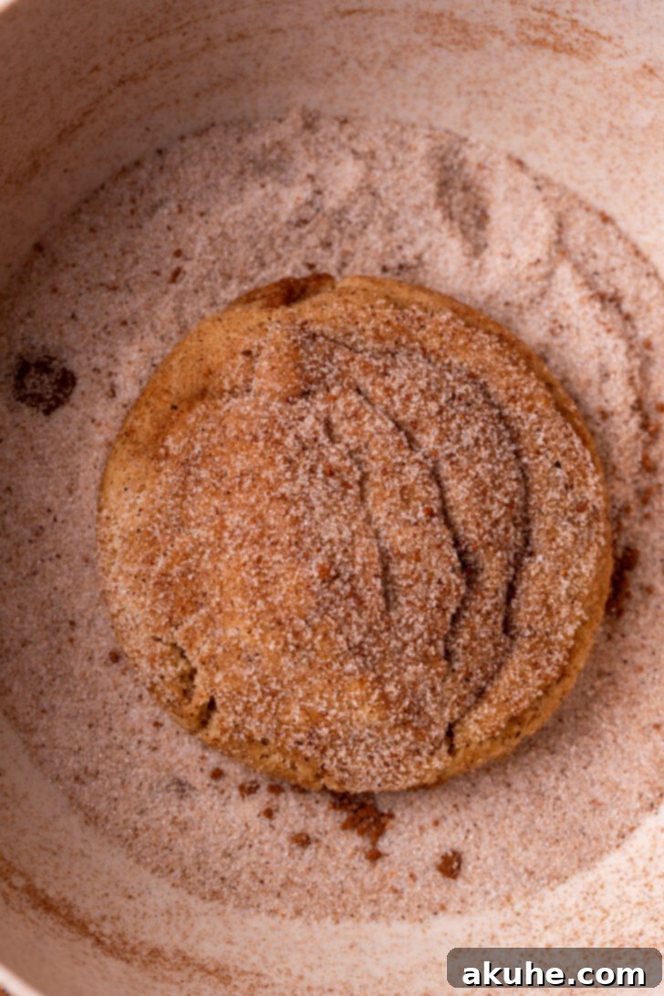 Spiced Chai Cookies 7 A baked chai cookie being rolled a second time in a bowl of chai sugar.