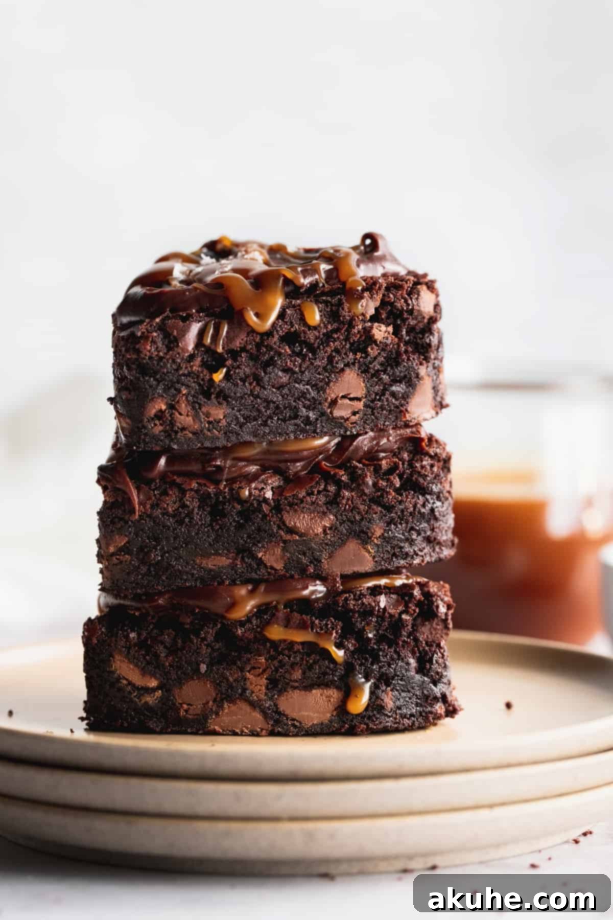 A stack of three individual fudgy brownies, showcasing their thick, dense interior and glistening chocolate chips.