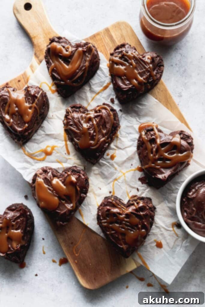 Heart-shaped brownies beautifully topped with chocolate ganache and a delicate drizzle of homemade salted caramel, ready for serving.