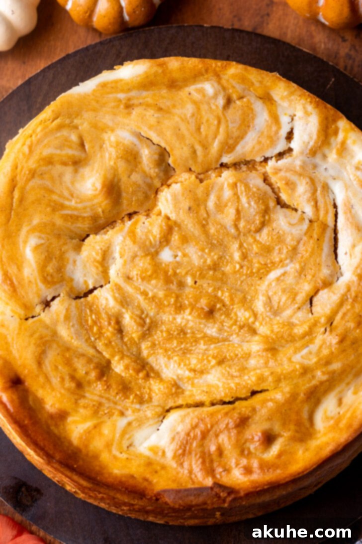 Autumn Pumpkin Cheesecake Cake 8 Baked pumpkin cheesecake cake on a wooden board, showing minor cracks on top.