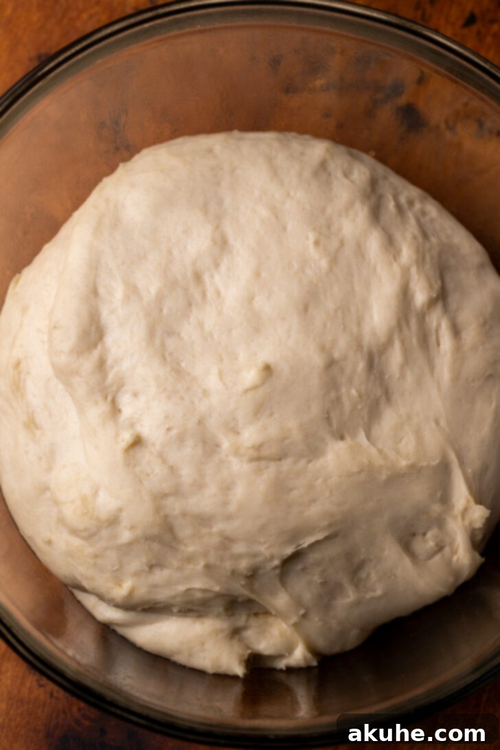The perfectly risen dough after its first proofing, having beautifully doubled in size within a mixing bowl, showcasing perfect yeast activation and readiness.