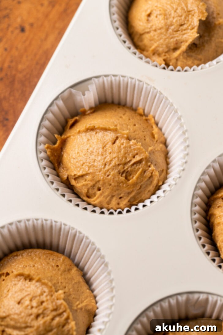 Warm Gingerbread Delights 5 Cupcake batter neatly scooped into paper liners within a muffin pan, ready for the oven.