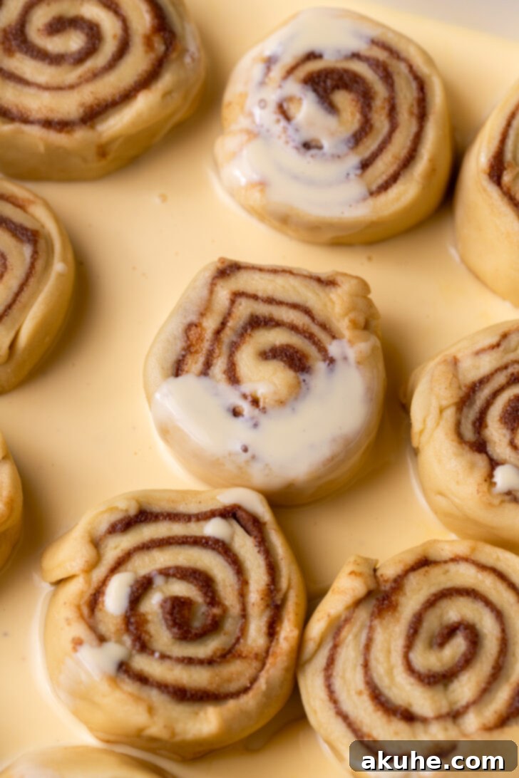 Festive Eggnog Swirls 7 Pouring eggnog around the raw cinnamon rolls in the baking pan before the second rise and baking.