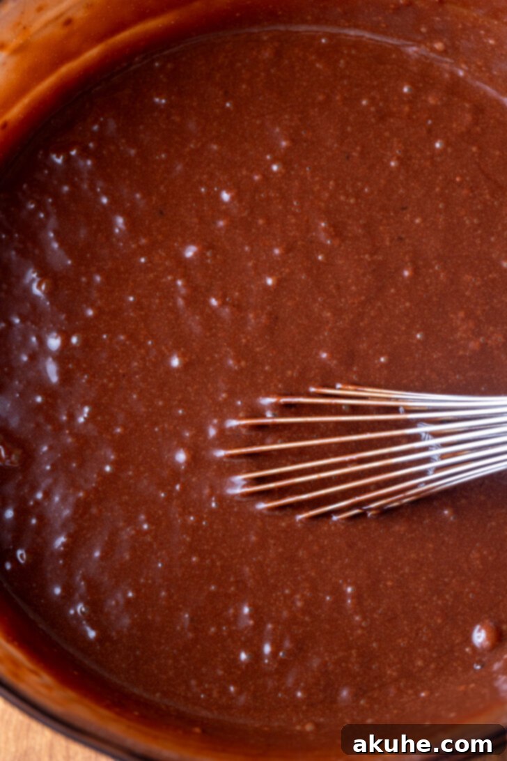 Chocolate cake batter in a mixing bowl, ready to be poured into cake pans.