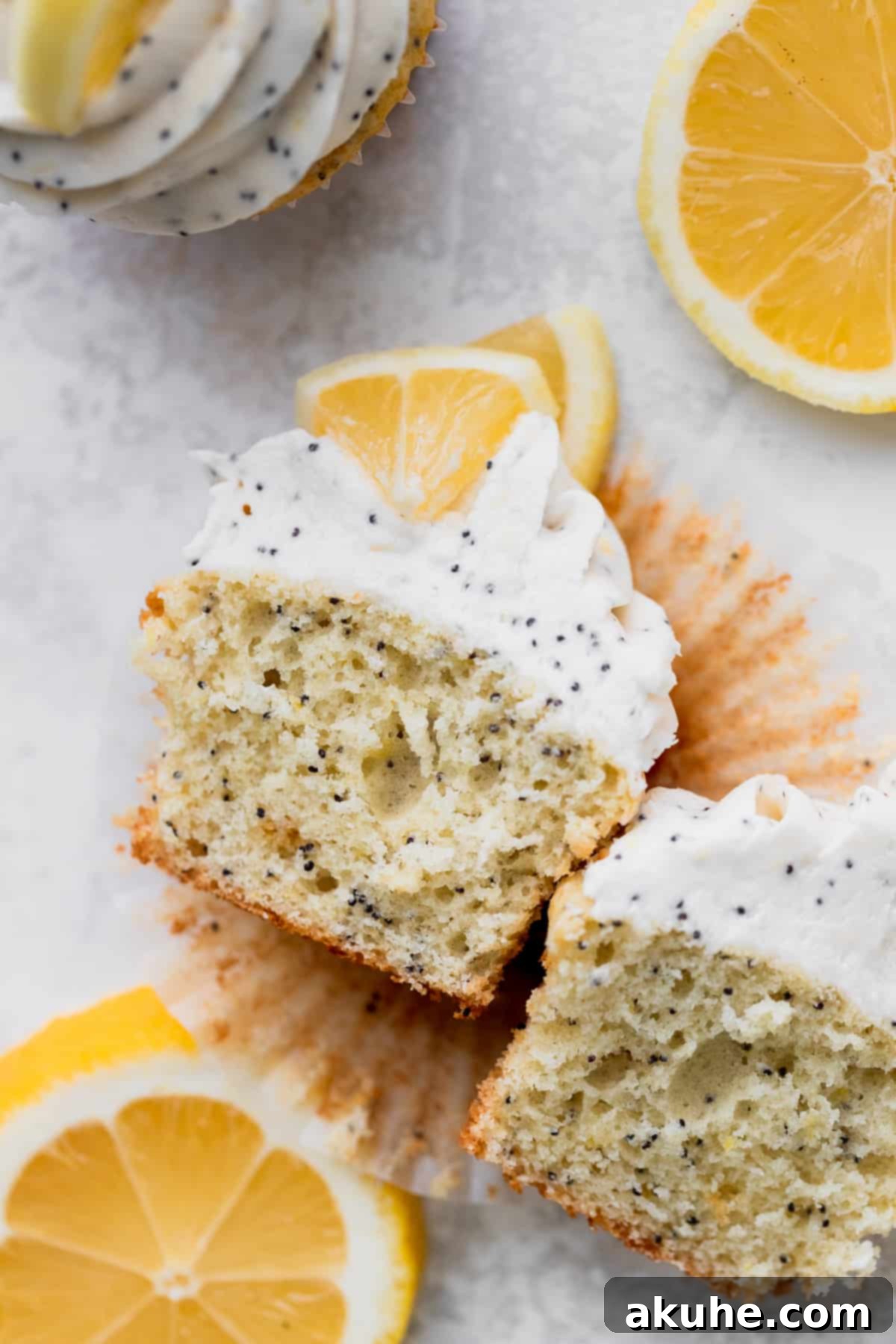 Sunshine Lemon Poppy Seed Cupcakes 2 Lemon poppy seed cupcakes split in half, revealing their moist texture and speckles of poppy seeds.