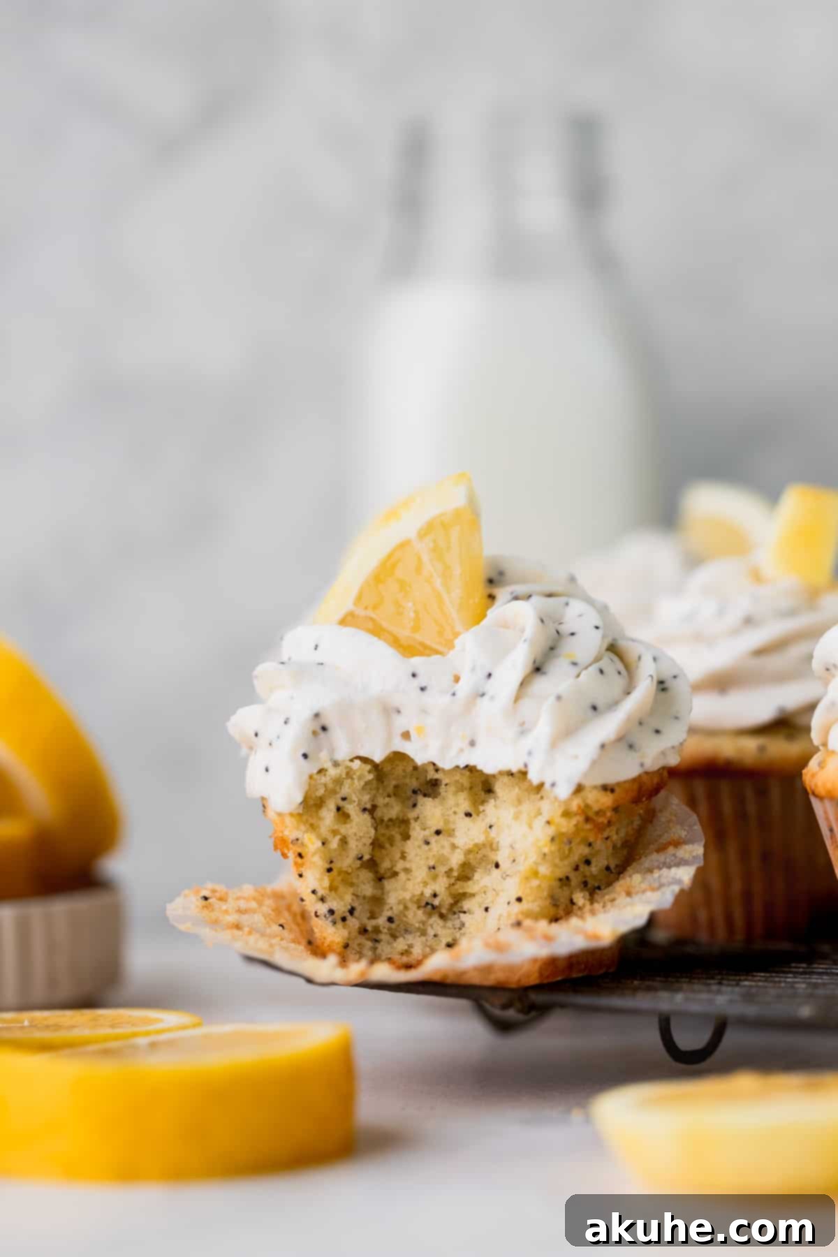 Sunshine Lemon Poppy Seed Cupcakes 3 A perfectly baked lemon poppy seed cupcake with a bite taken out, resting on a wire cooling rack.