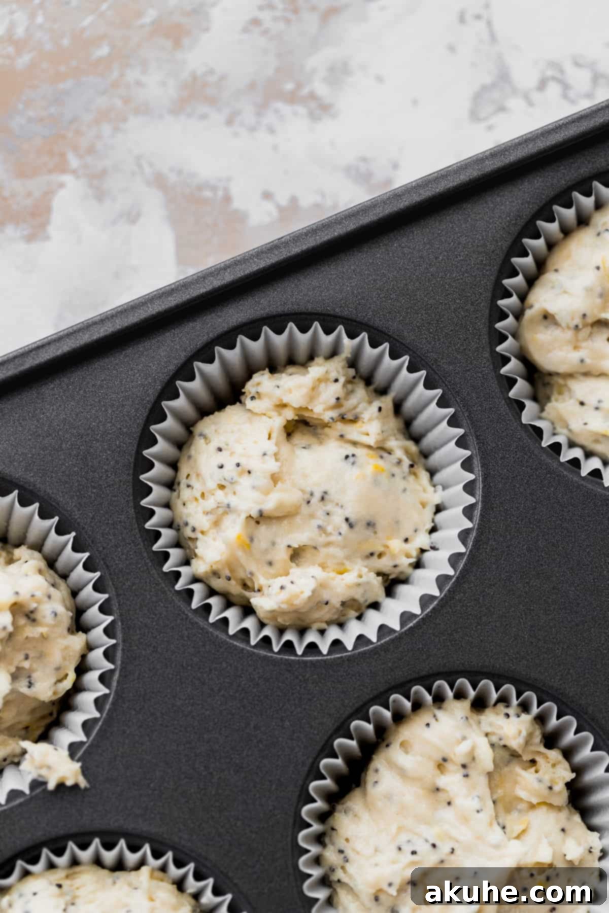 Sunshine Lemon Poppy Seed Cupcakes 6 Cupcake batter neatly scooped into a muffin tin with paper liners, ready for the oven.