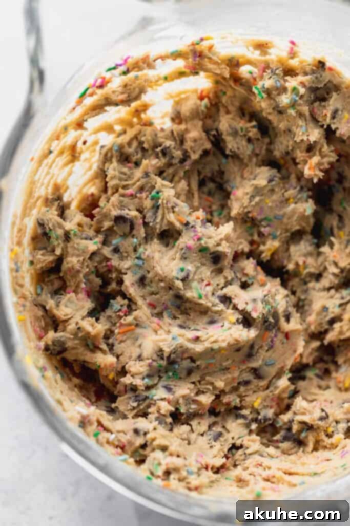 Cookie dough in a glass bowl, showcasing the mix of chocolate chips and rainbow sprinkles.