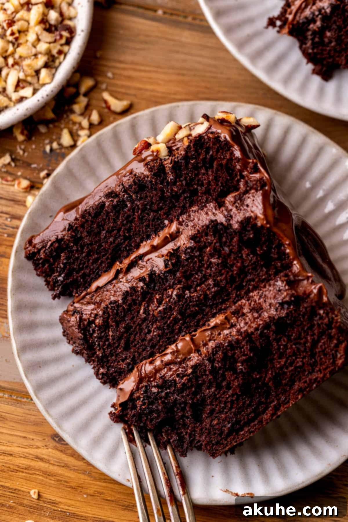 A pristine slice of Nutella cake, showcasing its distinct layers of chocolate cake, Nutella filling, and frosting, placed on a white plate.