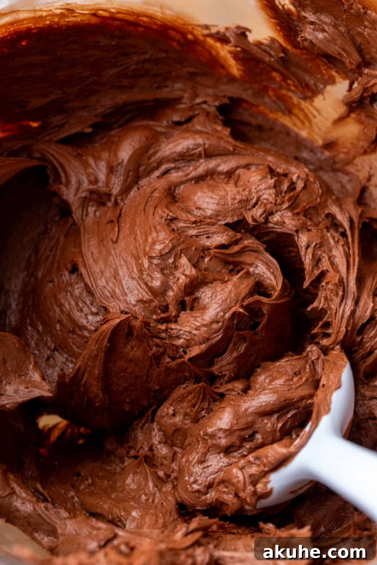 Lush Nutella frosting in a glass bowl, perfectly smooth and ready to be used.