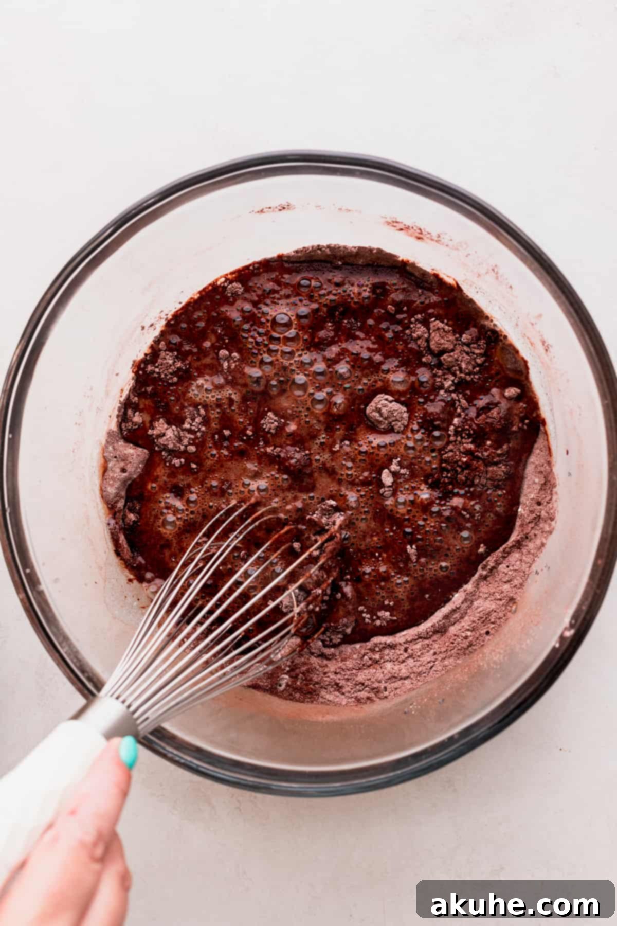 Wet ingredients being added to the chocolate cake batter.
