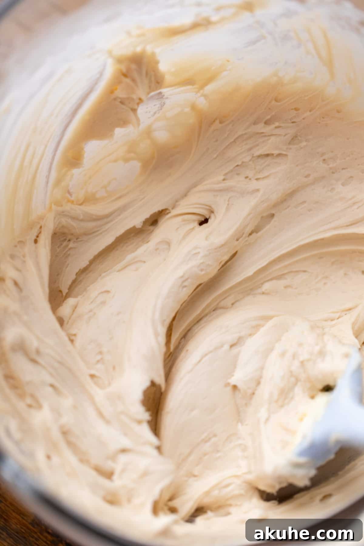 Maple Bacon Bliss Cupcakes 9 Rich, creamy maple cream cheese frosting in a clear glass bowl, showcasing its smooth texture.