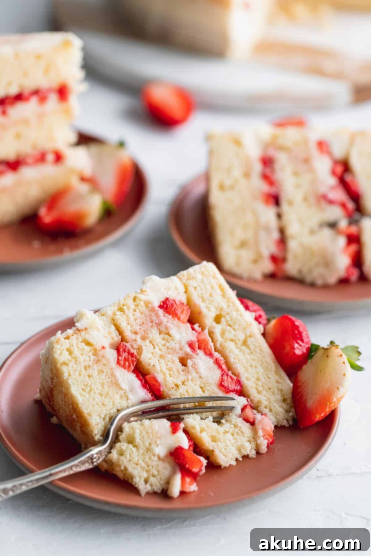 Elegantly Undressed Strawberry Cake 3 Cake slices on pink plates.