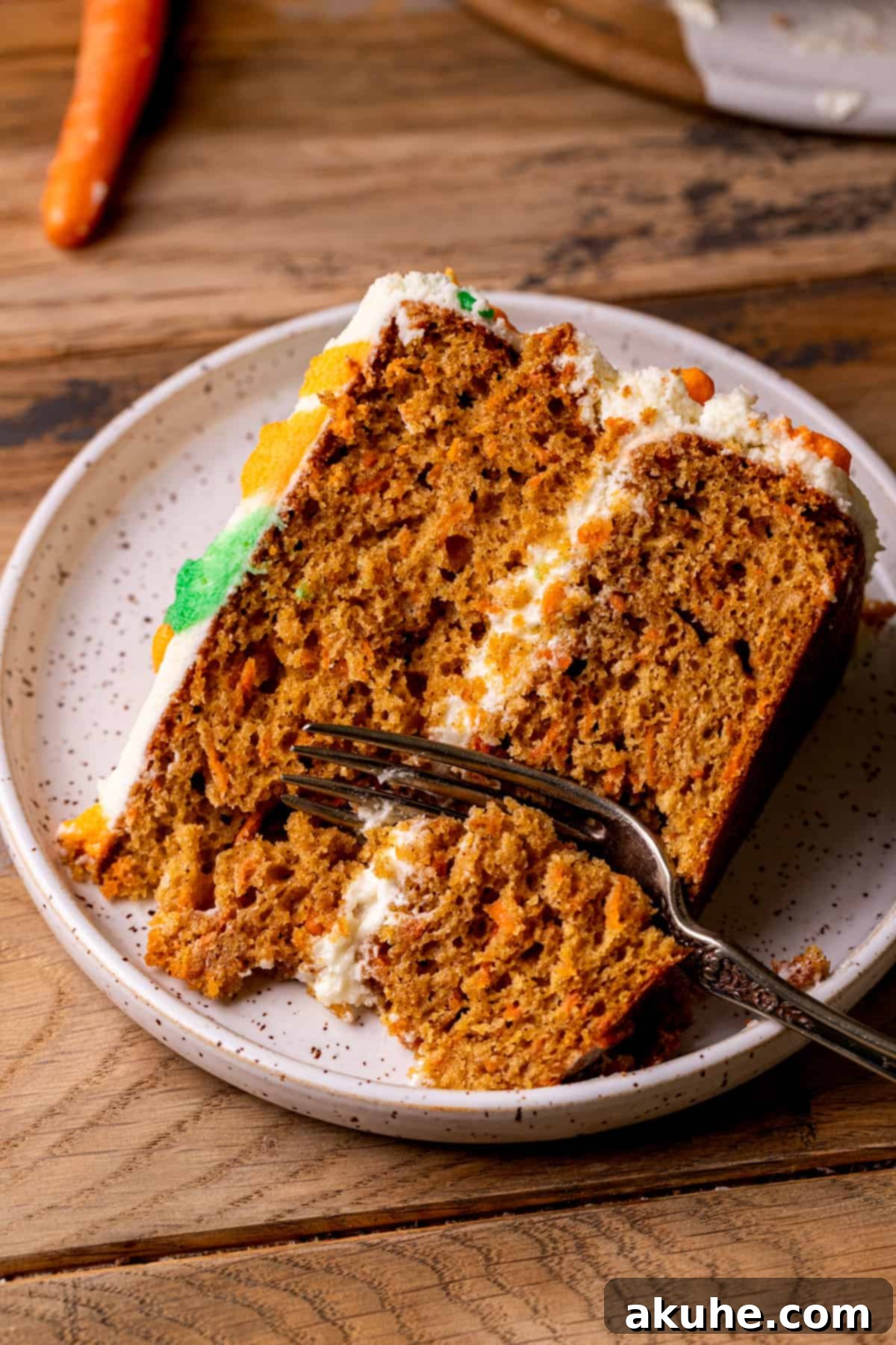 Heavenly Carrot Cake 2 A perfectly sliced piece of the best carrot cake, showcasing its moist layers and thick cream cheese frosting, with a fork gently inserted.