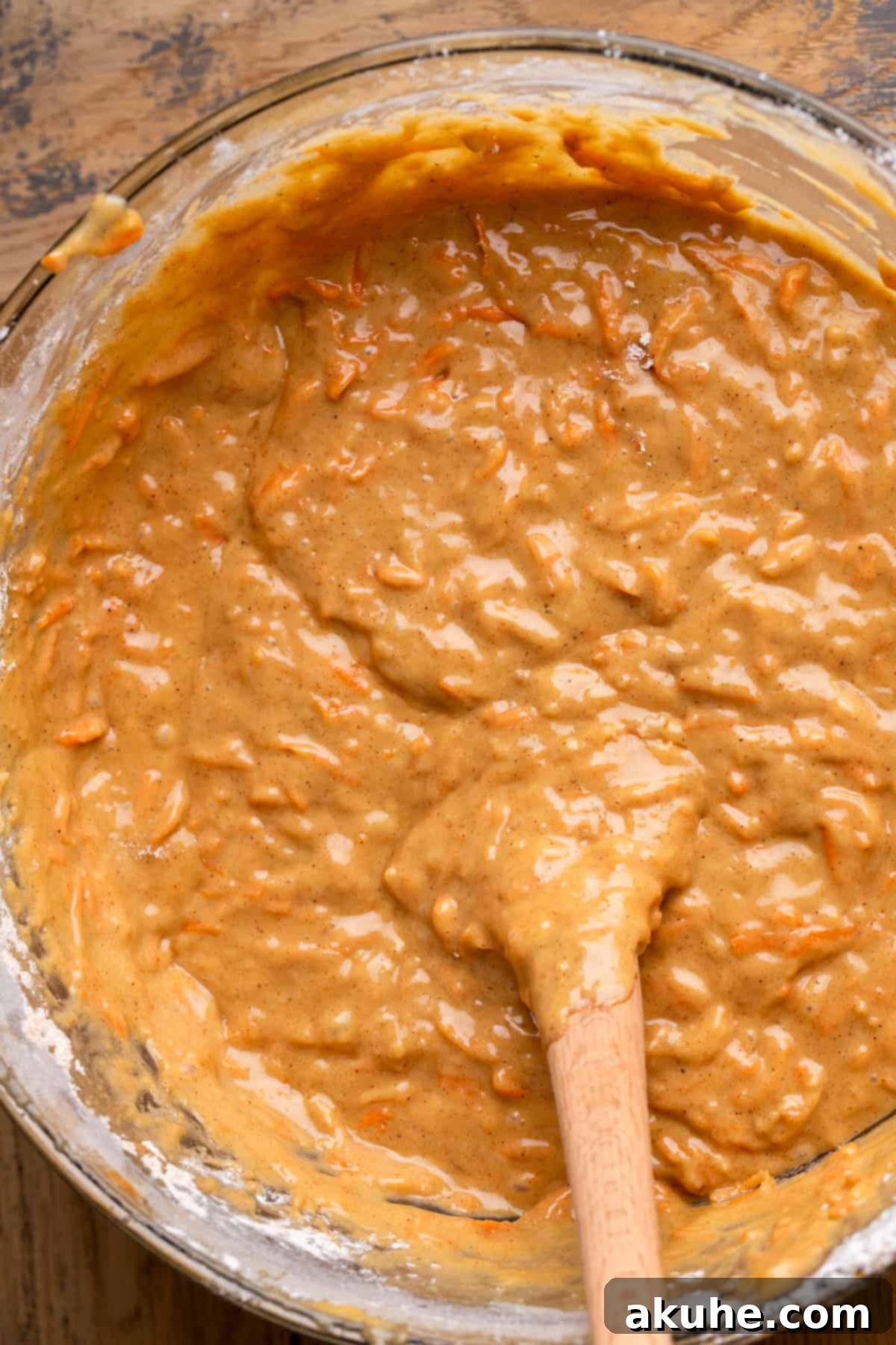 Heavenly Carrot Cake 5 Smooth, vibrant carrot cake batter filling a clear glass mixing bowl, showcasing its rich texture before baking.