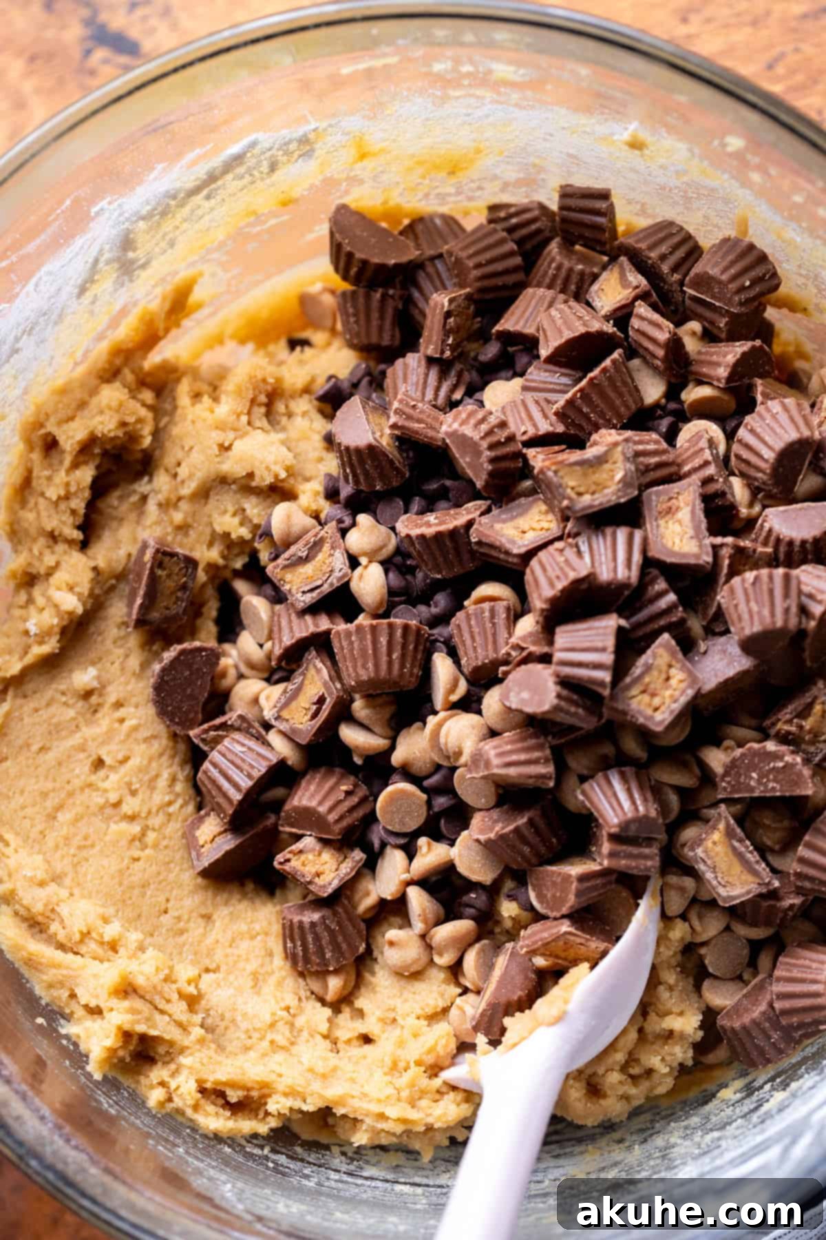 Ultimate Reese's Peanut Butter Chip Cookies 5 Chopped Reese's peanut butter cups being added to cookie dough in a mixing bowl.