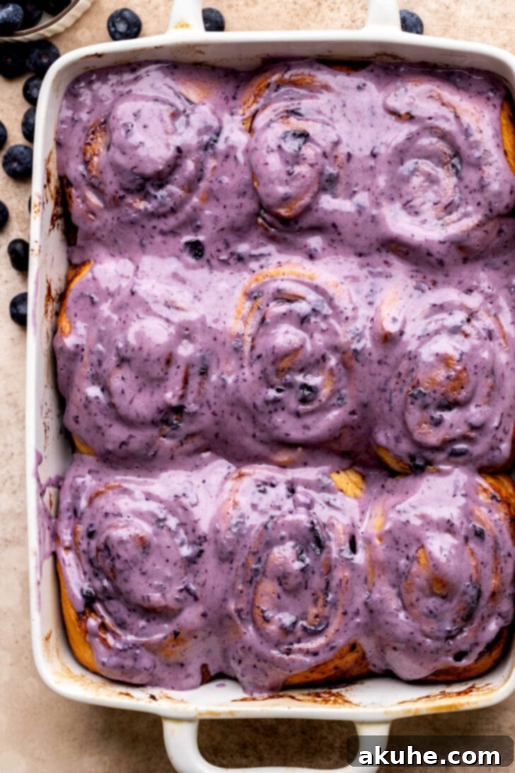 Top view of freshly baked blueberry cinnamon rolls with sweet cream cheese icing.