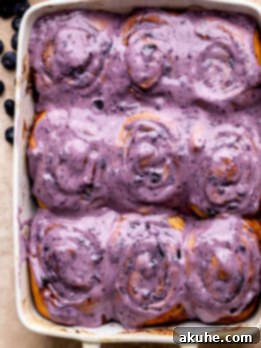 Top view of blueberry cinnamon rolls with icing in a pan.
