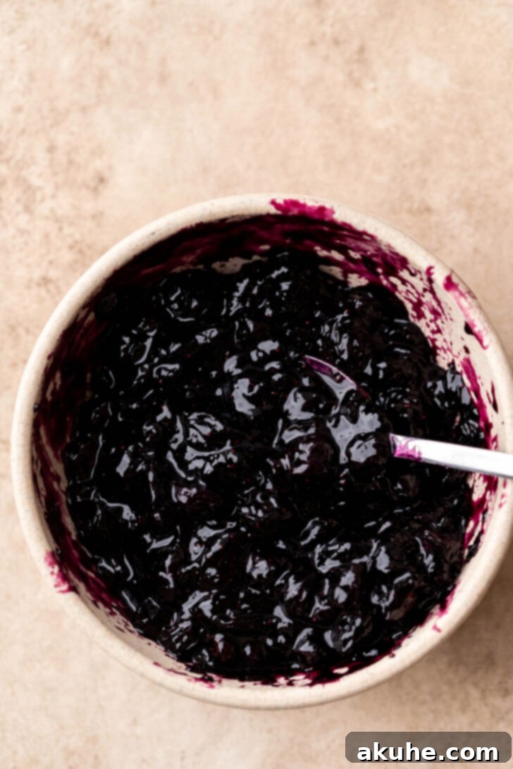 Chunky homemade blueberry jam in a clear bowl, ready to be spread.