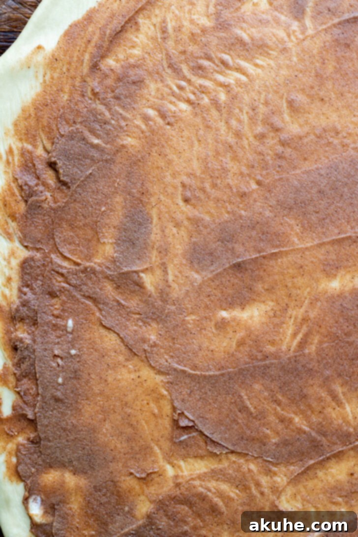 Smooth cinnamon filling spread evenly over the rolled-out dough.