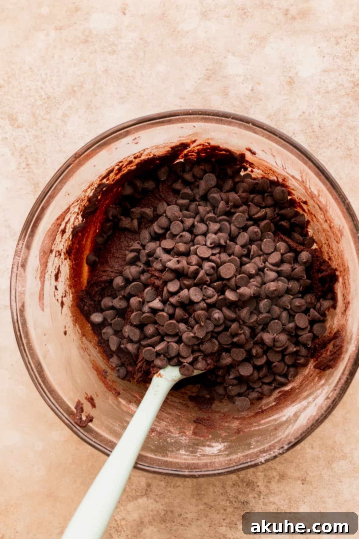 Chocolate chips on top of cookie dough, ready to be mixed.