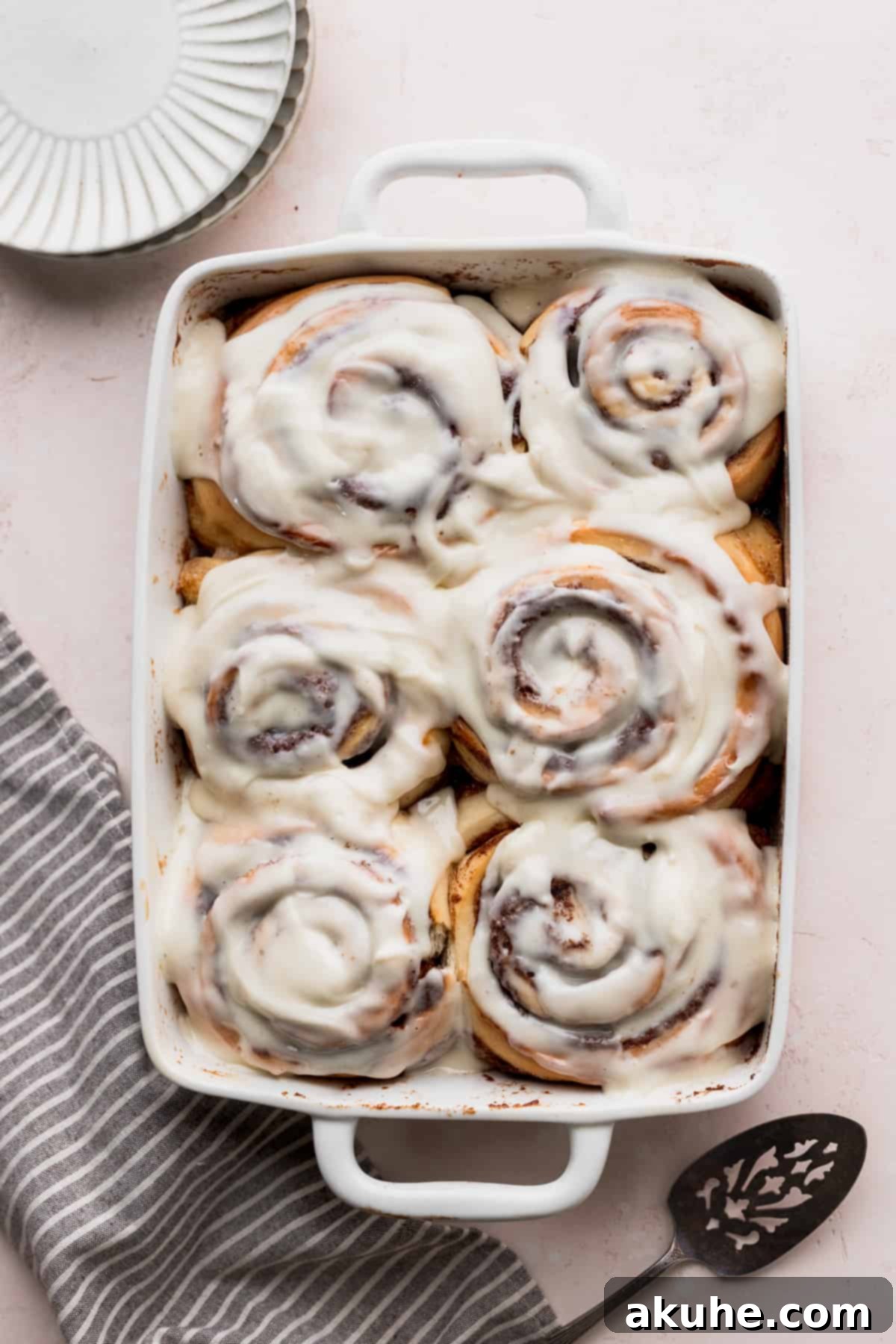 Colossal Cinnamon Buns 2 Giant fluffy cinnamon rolls in a pan with a spatula beside it.