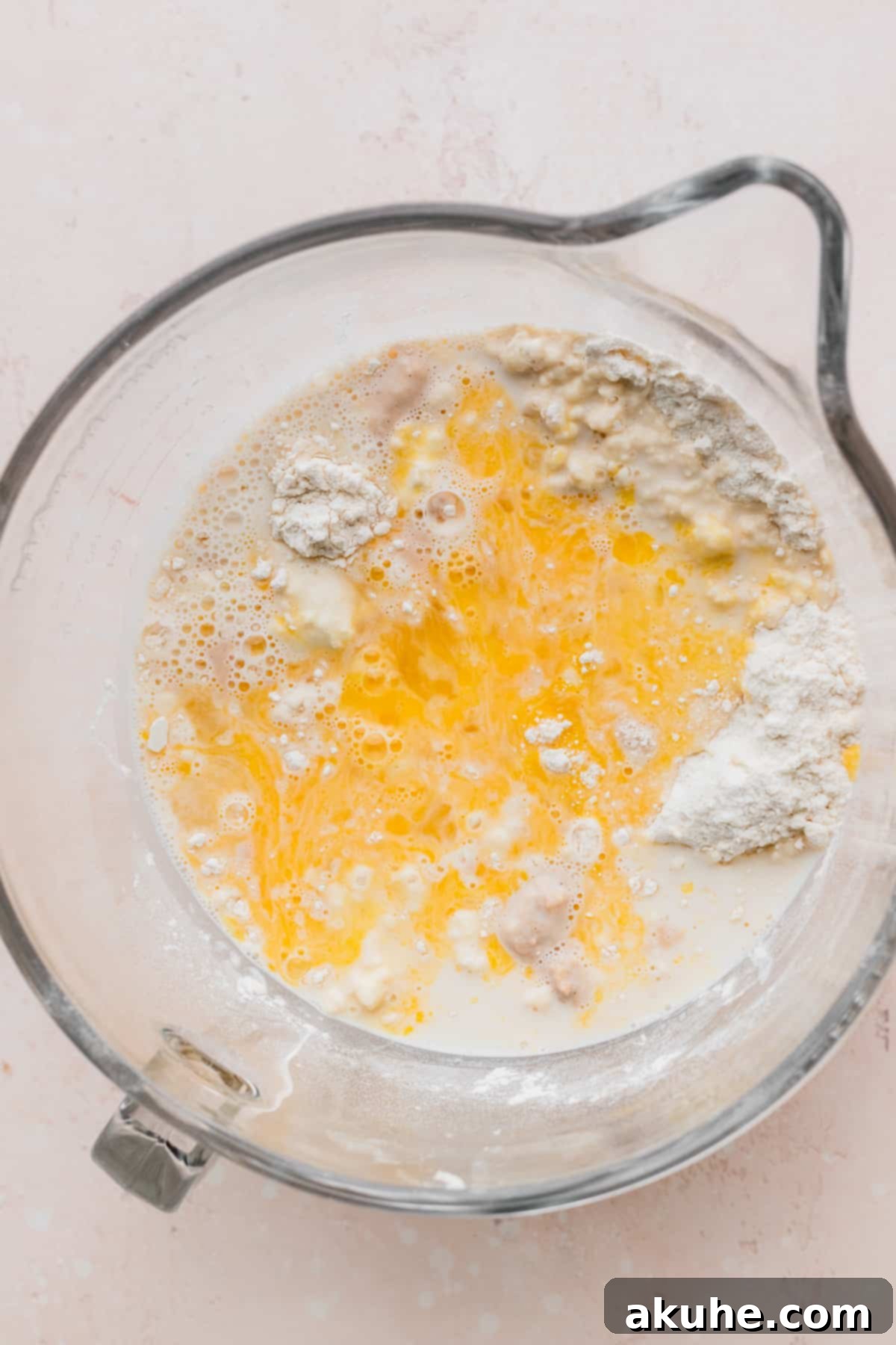 Colossal Cinnamon Buns 5 Wet ingredients added on top of dry ingredients in a glass bowl.