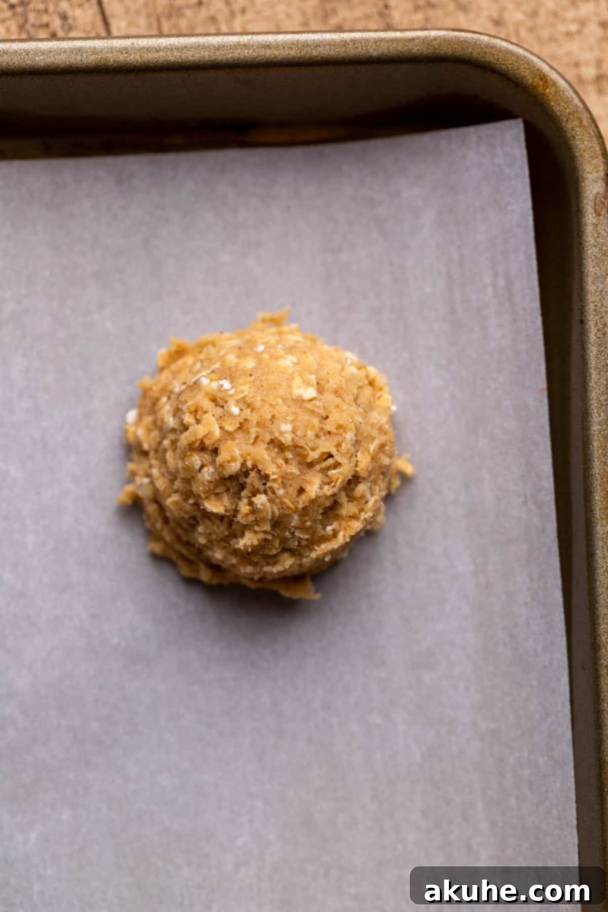 Classic Oatmeal Cream Cookies 6 A perfect ball of oatmeal cookie dough on a parchment-lined cookie sheet.