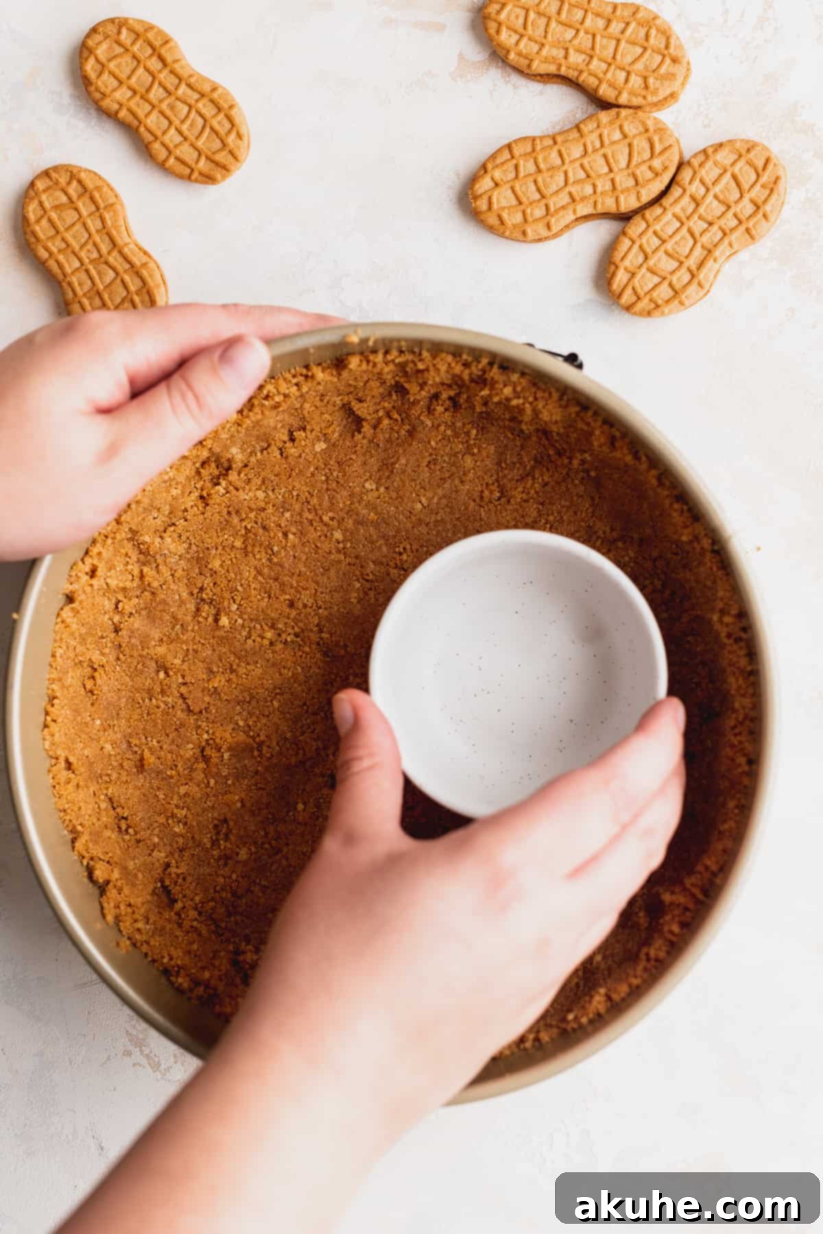 Pressing the Nutter Butter crumb mixture into the base of a springform pan.