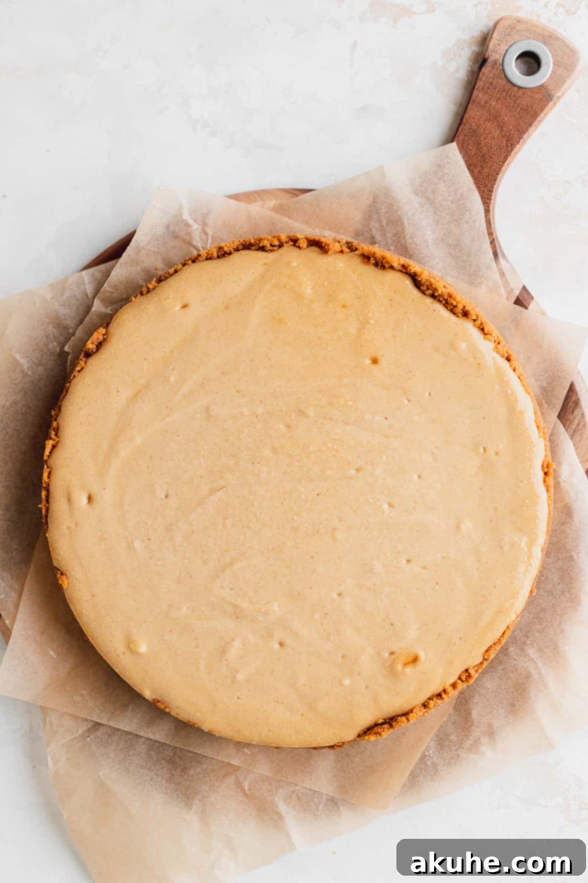 Baked peanut butter cheesecake cooling on a wooden tray.