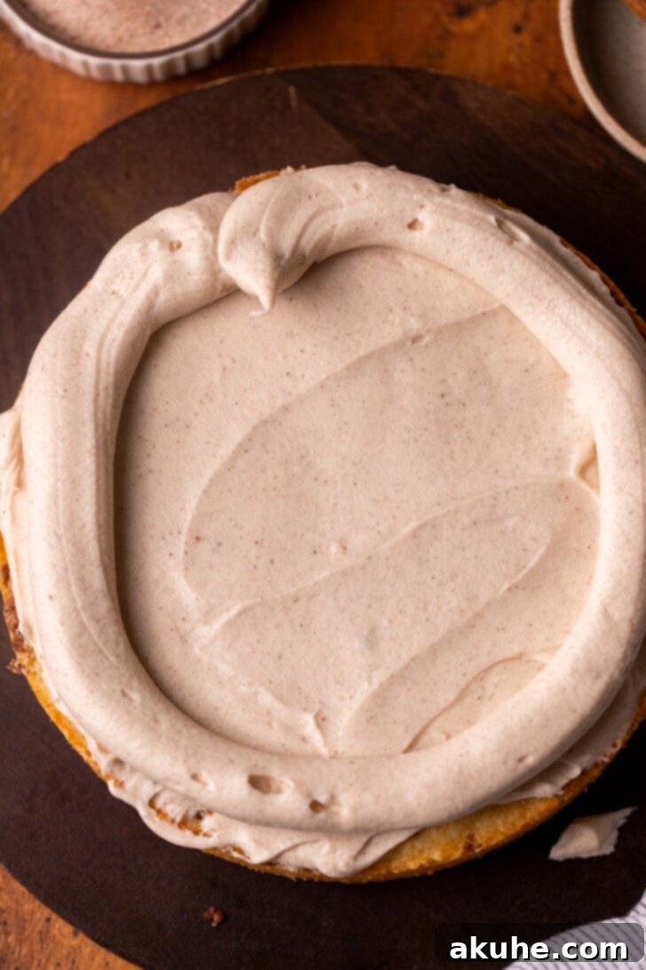 Golden Cinnamon Swirl Cake 11 A cake layer with frosting smoothly spread and a piped border created around the edge.
