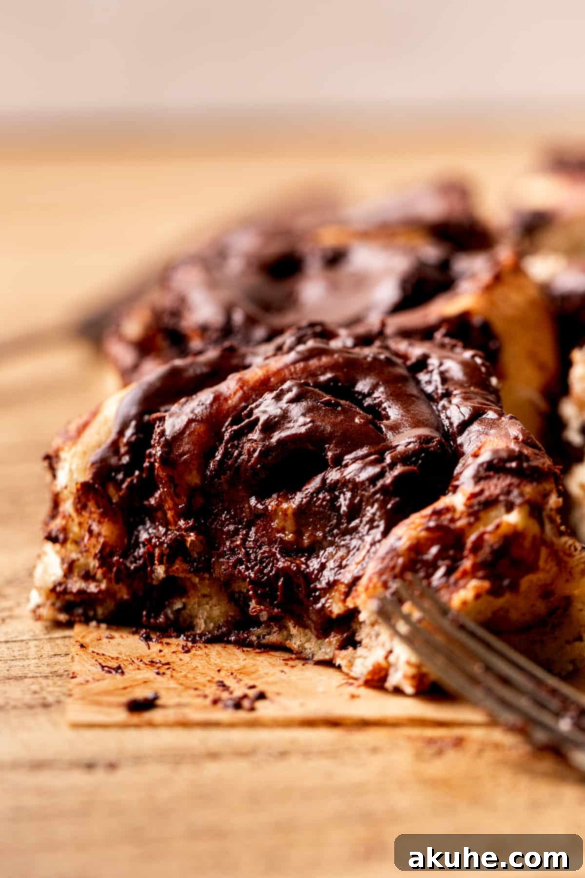 Chocolate Cinnamon Rolls 10 A side view of a chocolate cinnamon roll with a delicious bite taken out, showing its gooey interior.