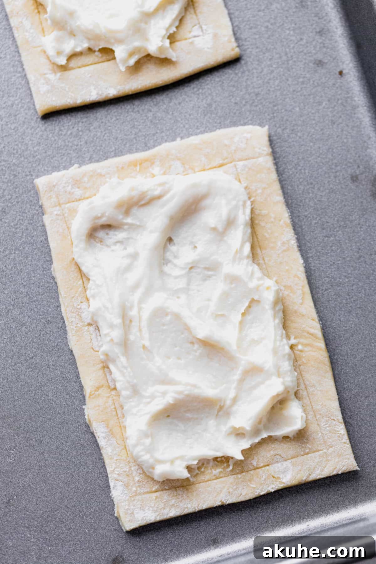 Cream cheese filling spread onto a scored puff pastry rectangle.