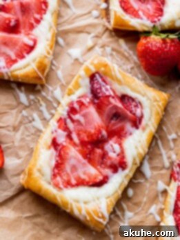 Strawberry danish on parchment paper with lemon glaze on top.
