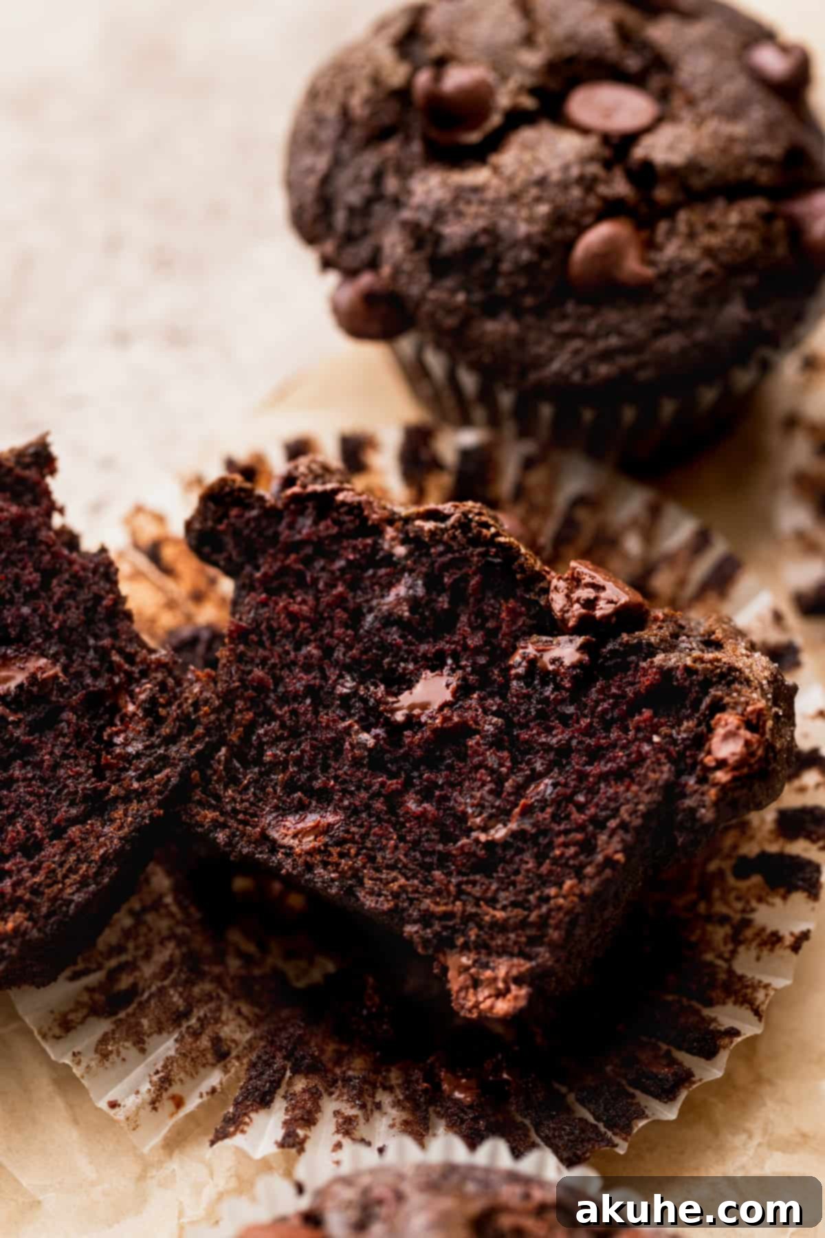 Decadent Triple Chocolate Muffins 9 A triple chocolate muffin cut in half showing the melted chocolate chips inside.