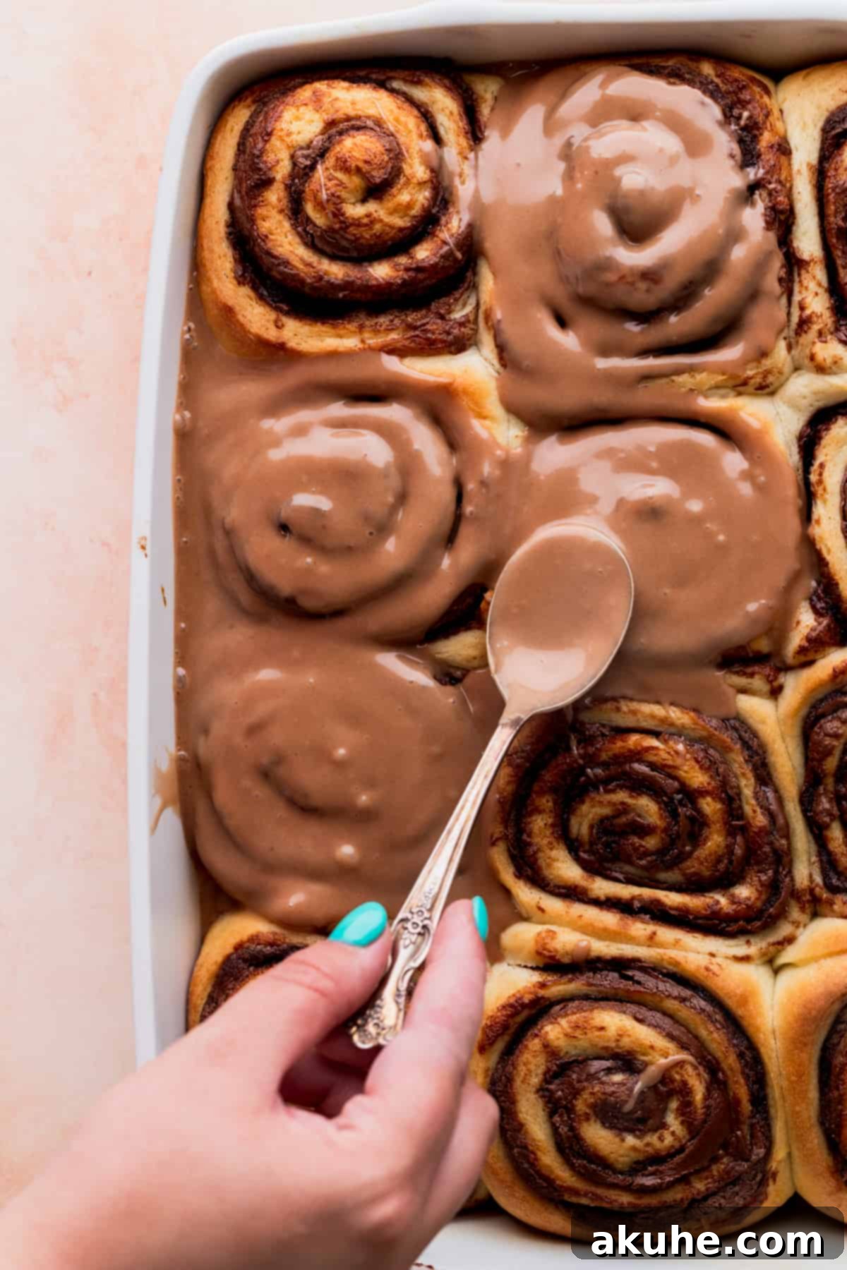 Spreading Nutella icing on top of the Nutella rolls, showcasing their gooey texture.